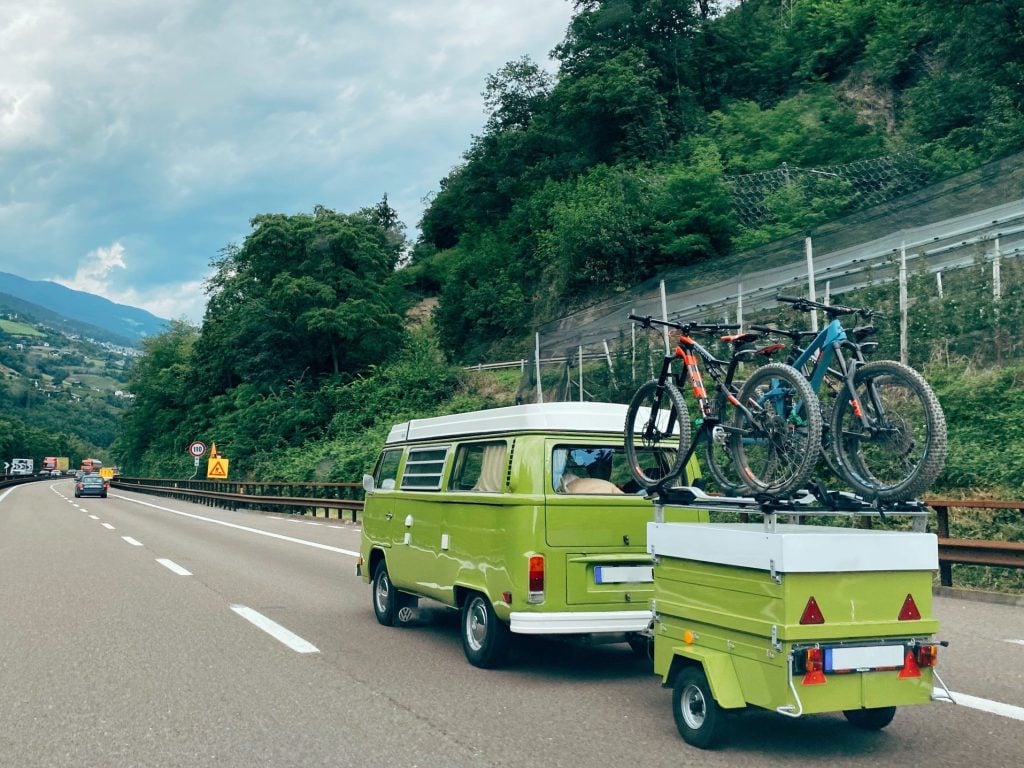 Green Volkswagon bus and trailer driving down Interstate 80