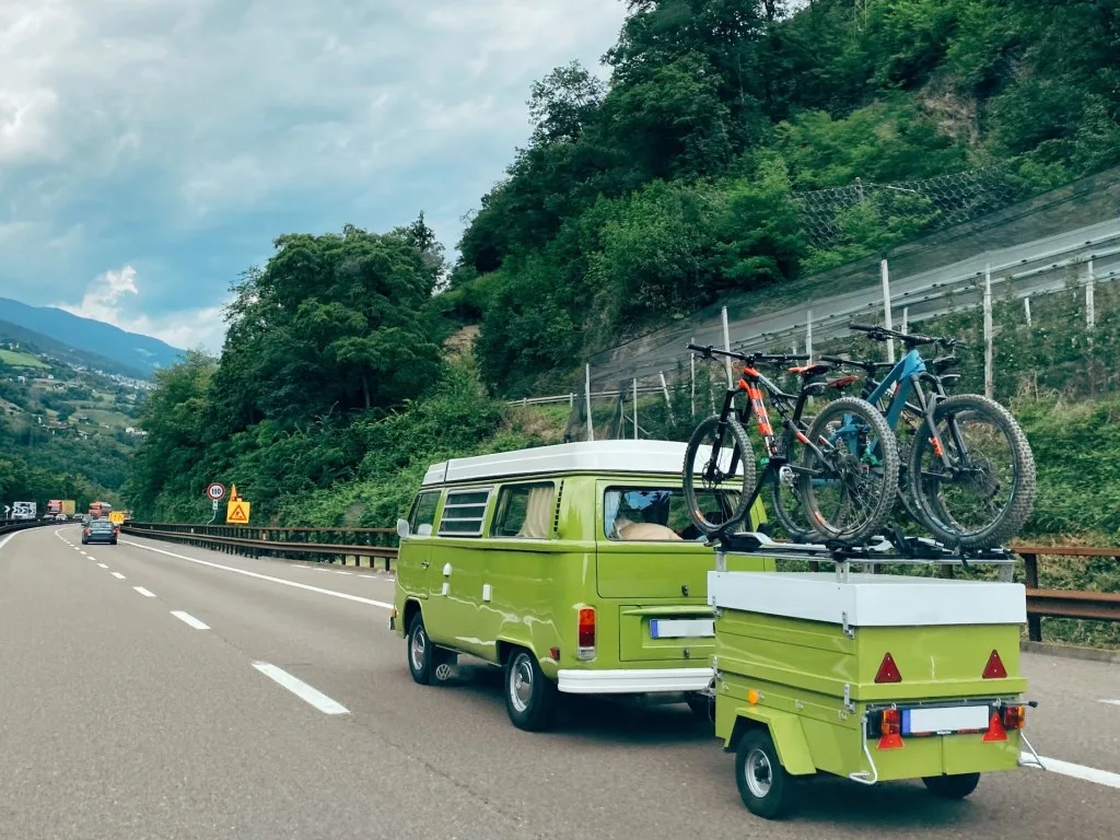 Green Volkswagon bus and trailer driving down Interstate 80