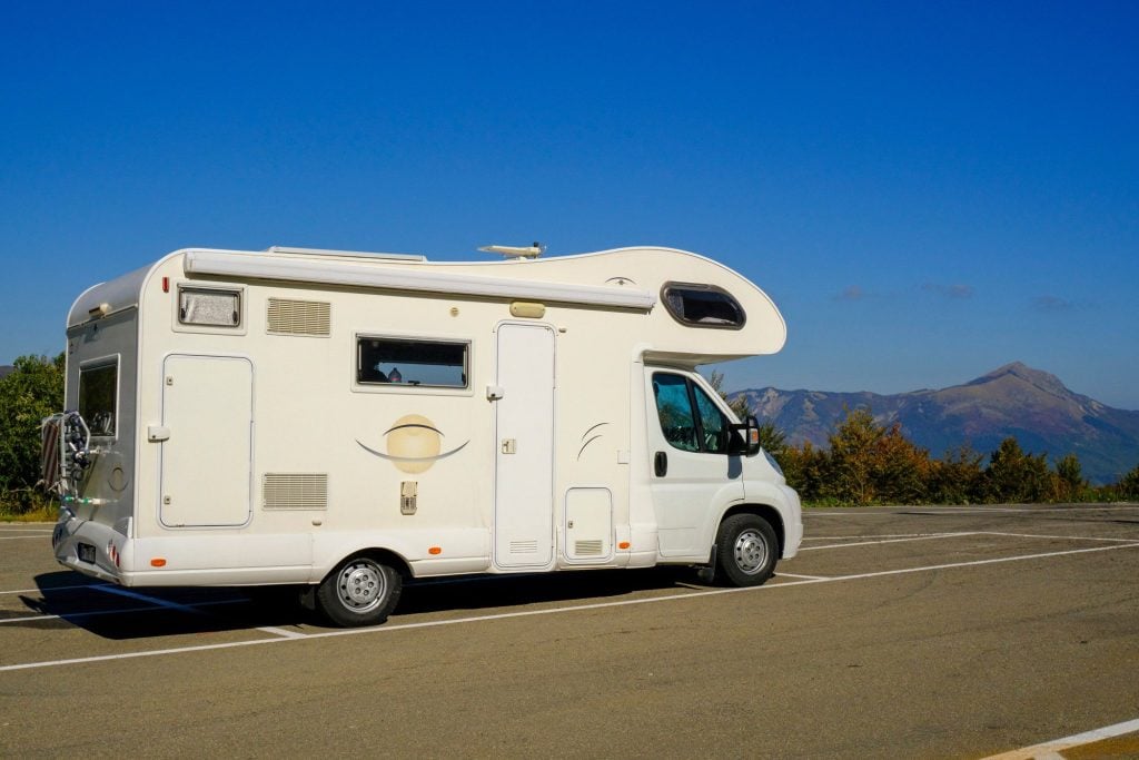 RV parked in parking lot next to mountains