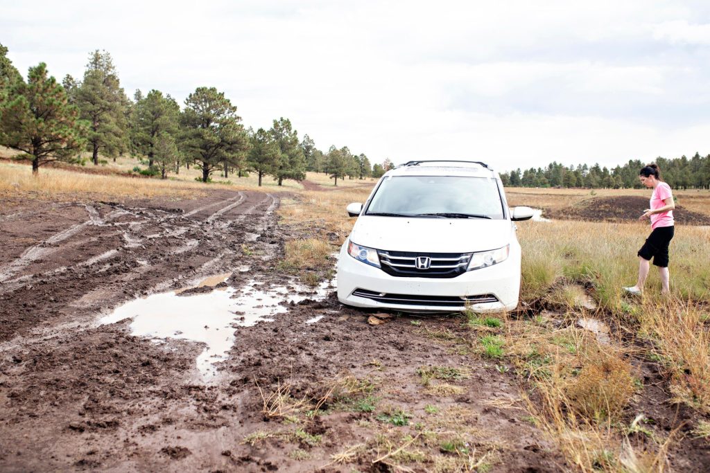 Woman standing next to Honda SUV stuck in mud