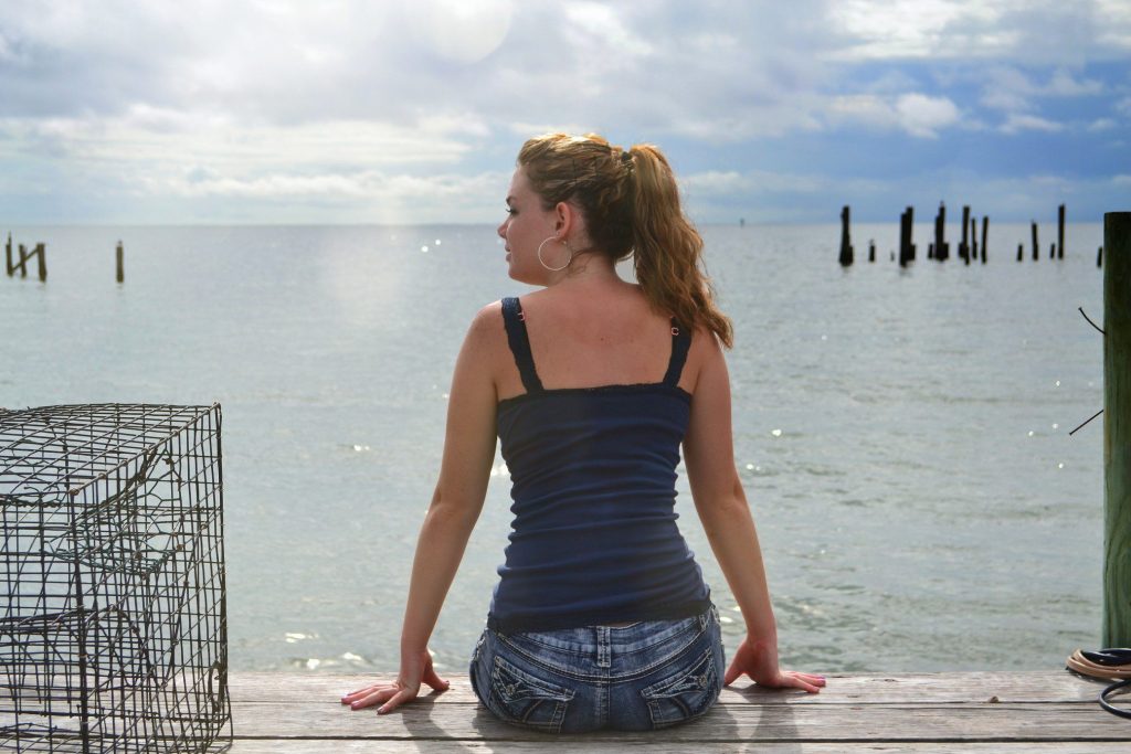 Woman sitting on pier looking at Chesapeake Bay. 