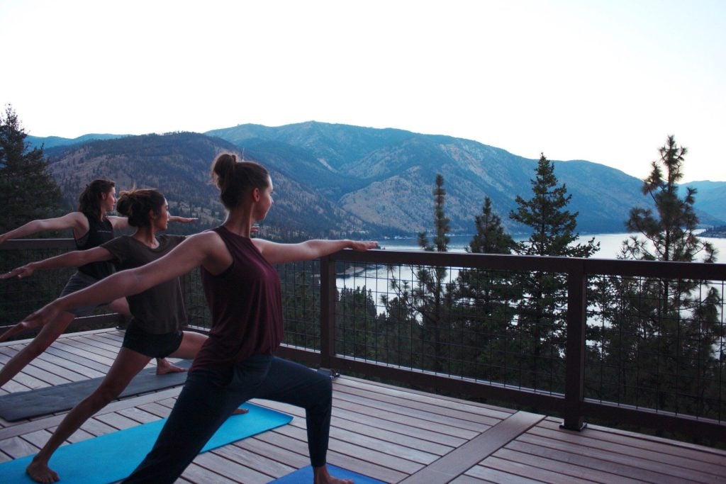 Three women doing yoga together next to Lake Chelan