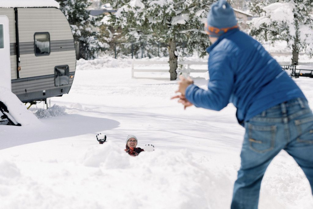 Father throwing snowball at son in fron tof RV