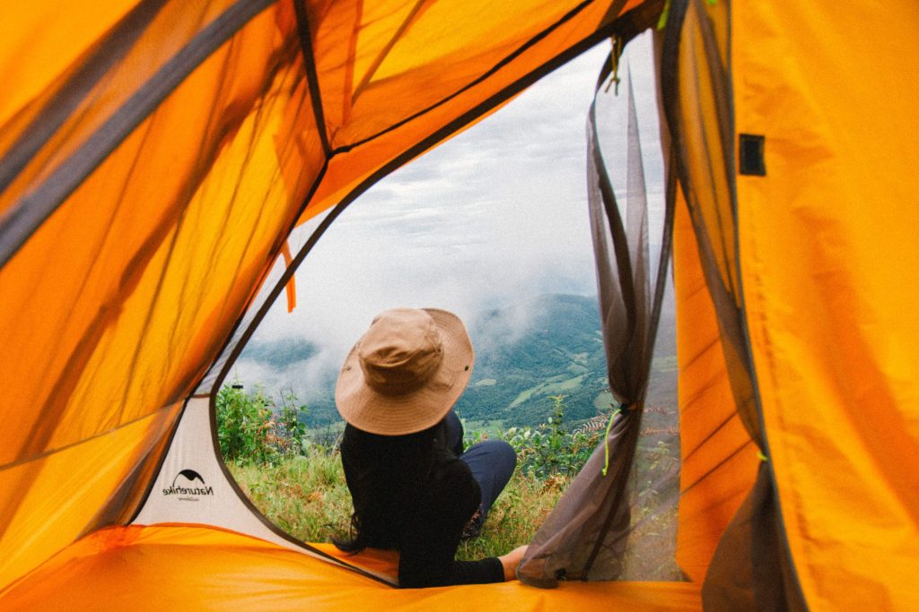 Woman laying looking out through tent at foggy mountains