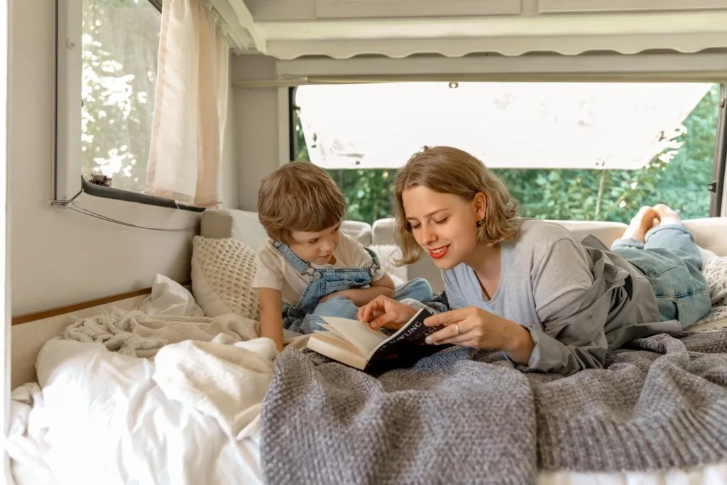 Mom reading to son while laying inside RV