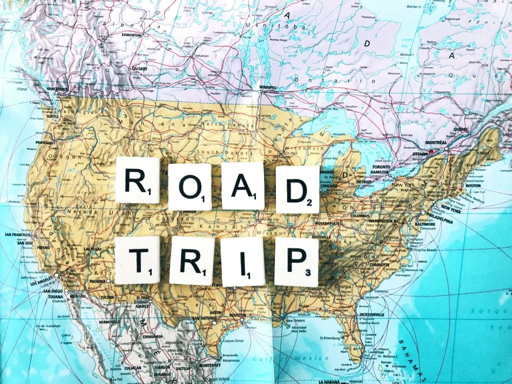 Map of USA with the word road trip spelled out with scrabble tiles