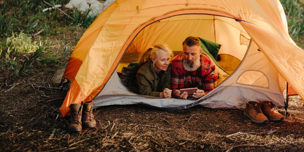 Older couple laying together in tent while camping