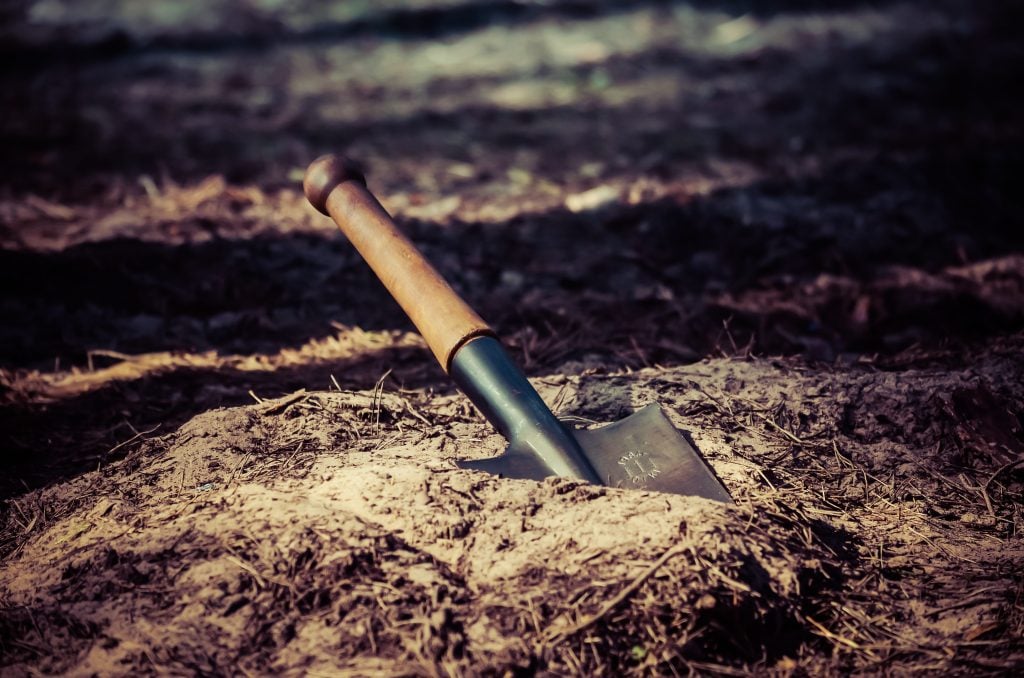 Camping shovel digging hole to use the bathroom while camping