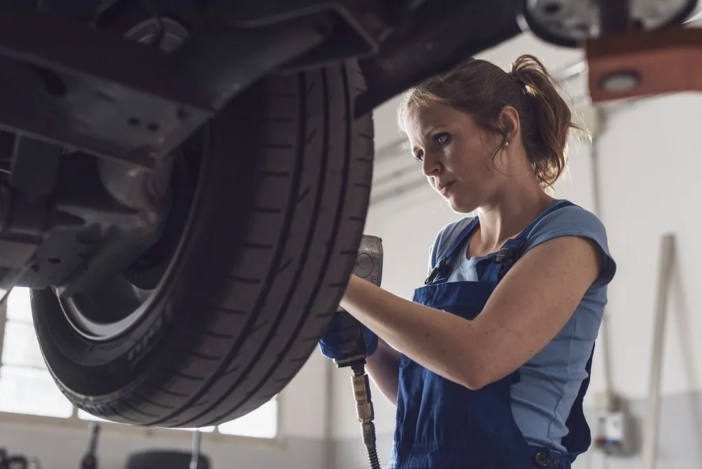 Woman checking tire tread on vehicle