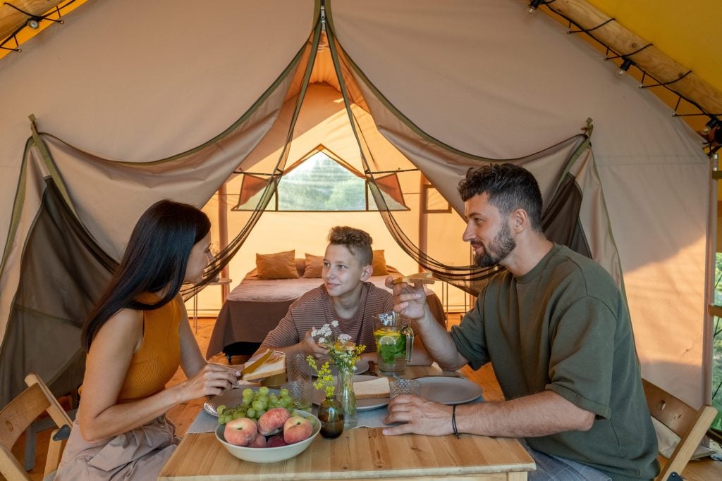 Mother, father, and son eating meal in a glamping tent.