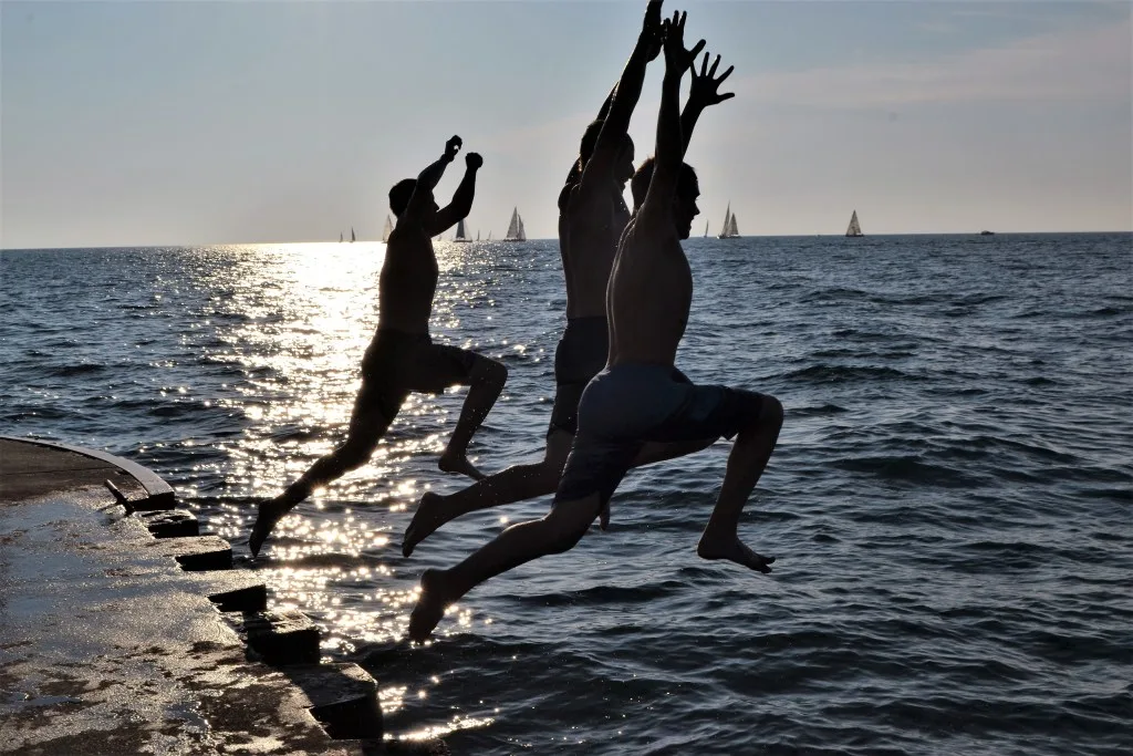 Friends jumping into choppy water in Lake Michigan