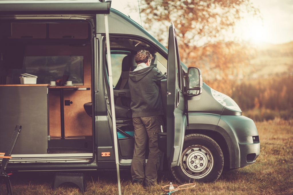 Older person looking inside camper van while camping in national park
