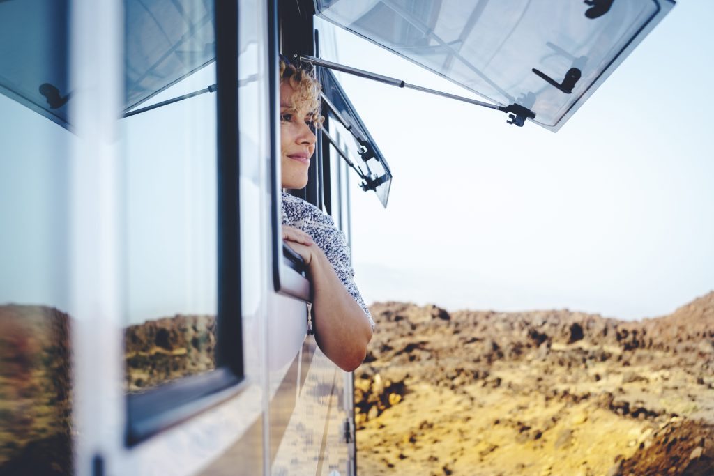 Woman learning out RV window while camping in the desert. 