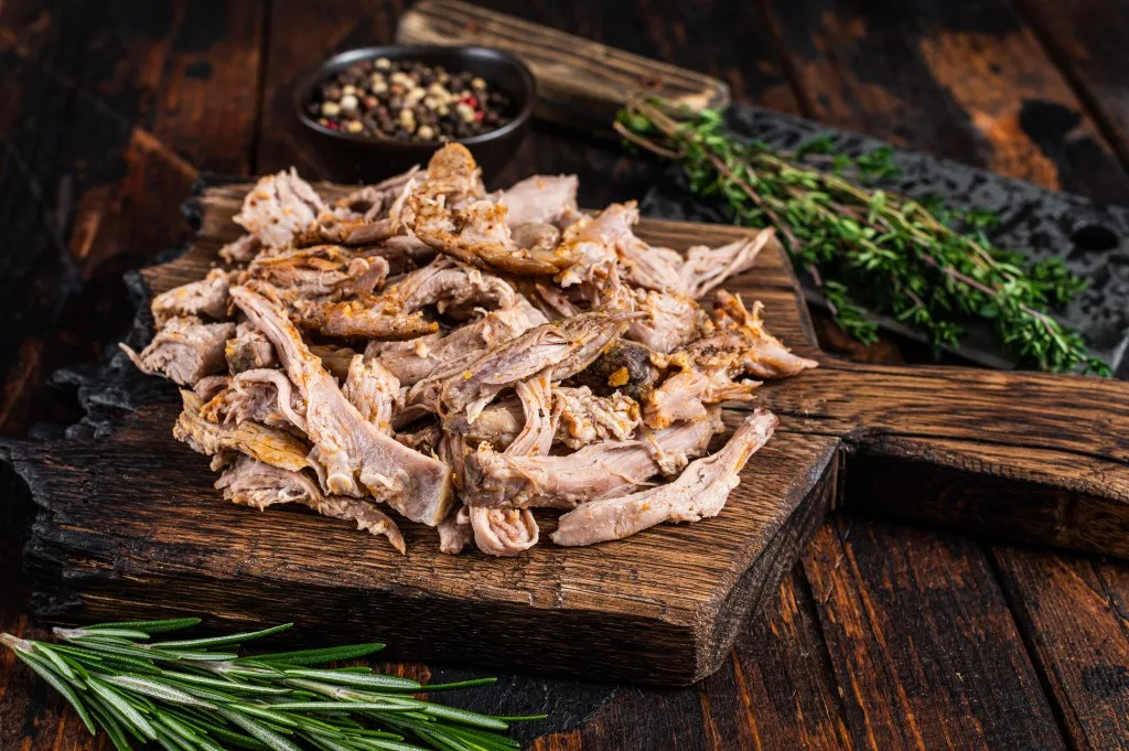 Pile of pulled pork on cutting board.