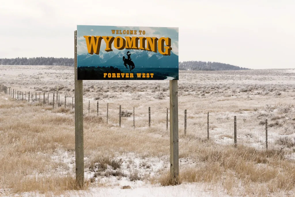 Welcome to Wyoming Forever West sign alongside road.
