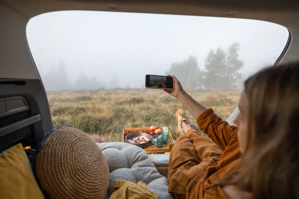 Woman taking selfie while laying in her car to car camp in.