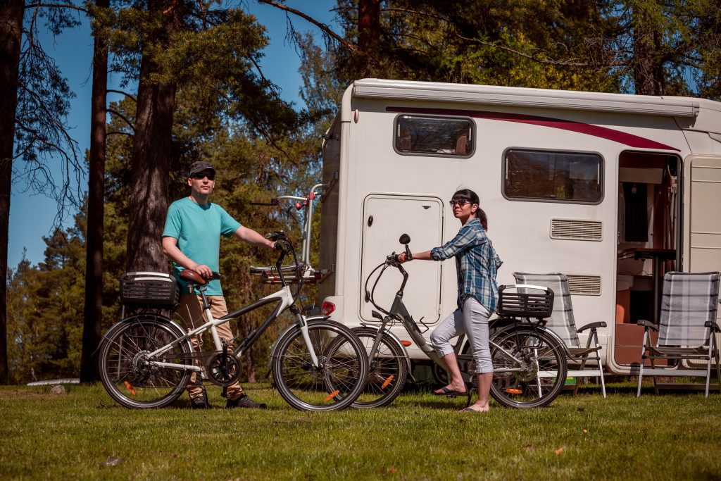Man and woman posing with e-bikes in front of RV