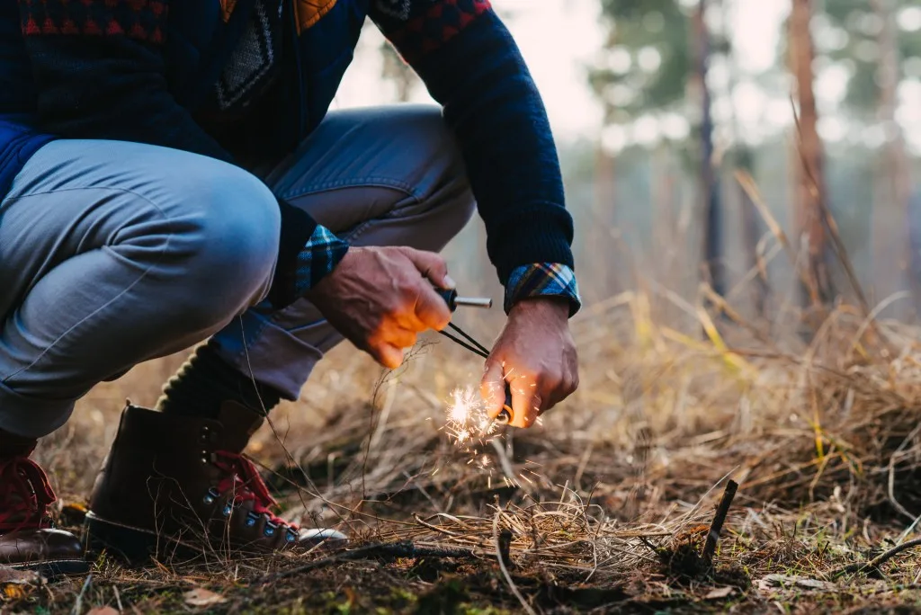 Man using fire starter to light a campfire