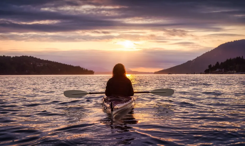 Woman kayaking at sunset along Mackinac Island coast