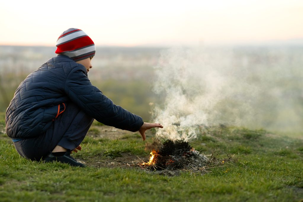 Boy building campfire while camping