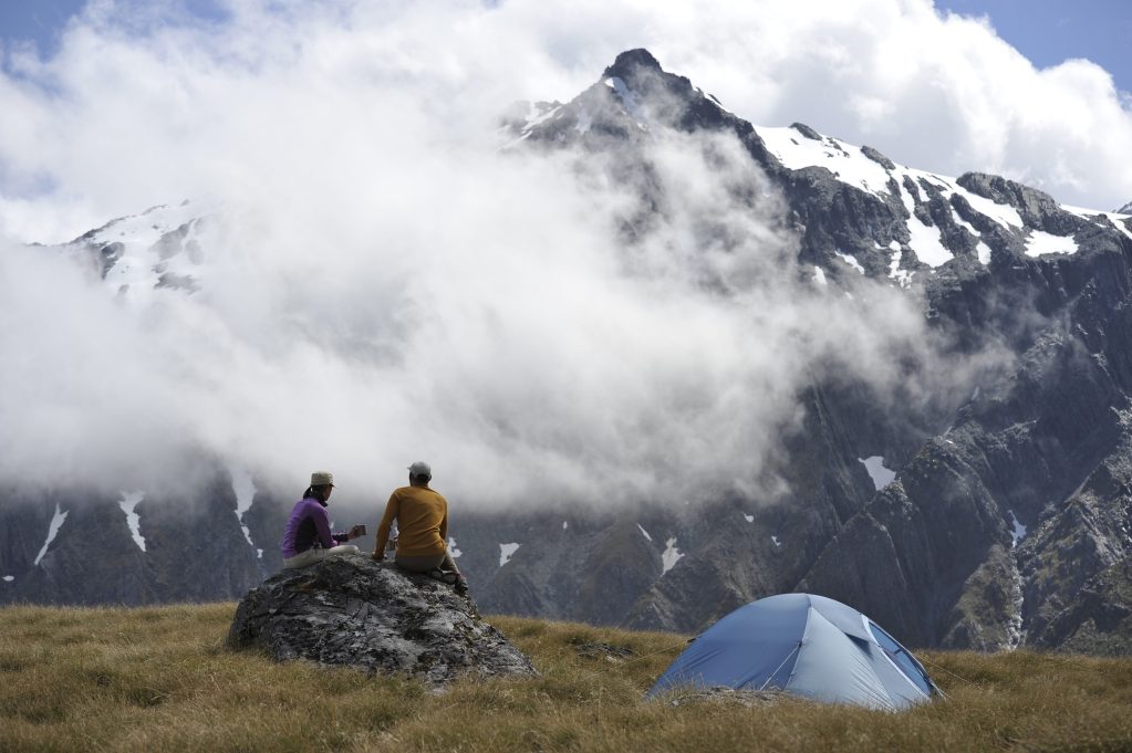 Couple tent camping at the base of a mountain.