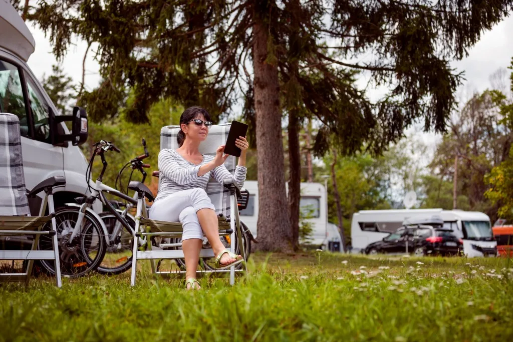 Woman relaxing in front of RV at campground.