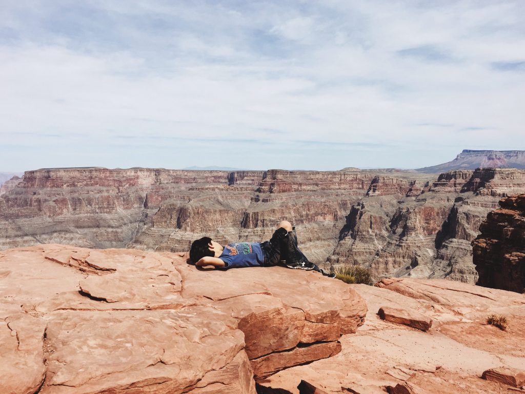 Kid laying on the edge of the Grand Canyon
