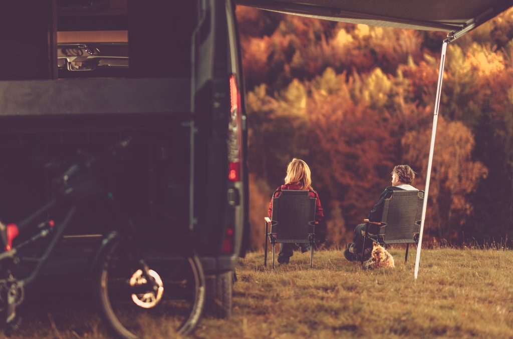 Couple sitting in front of RV in the fall