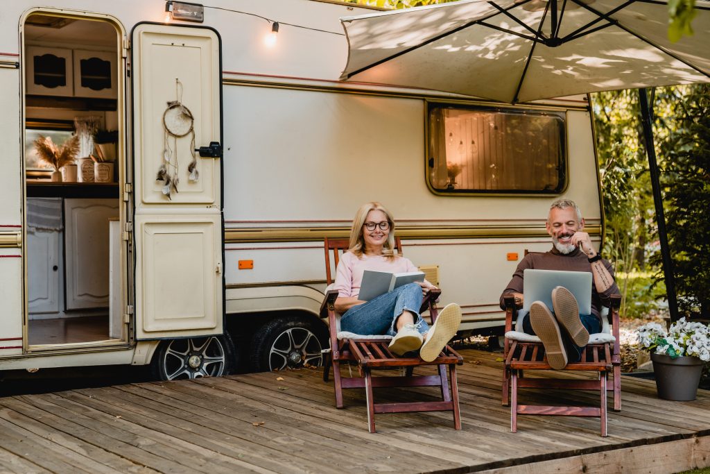 Couple using laptop while relaxing in front of RV