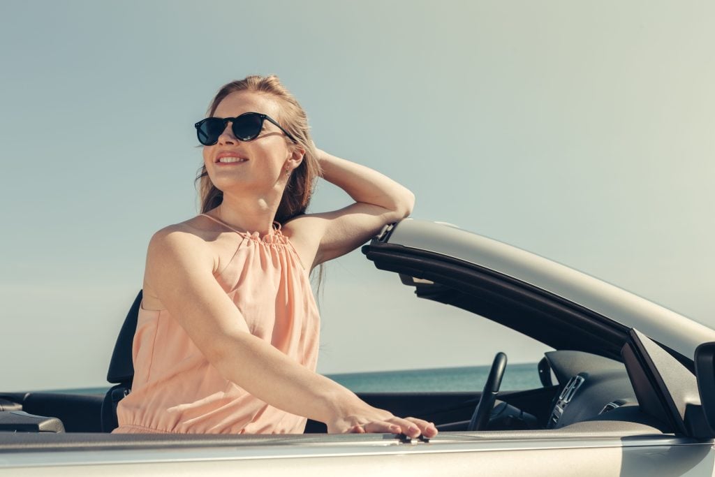 Young woman in convertible car driving along Pacific Coast Highway