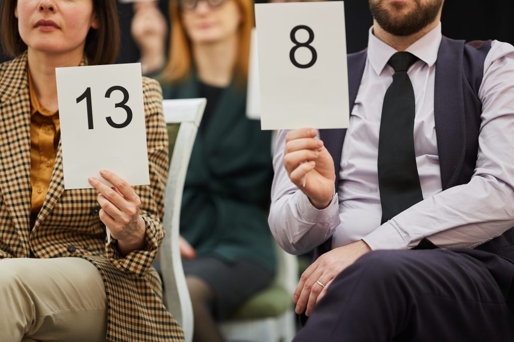 Close-up of people holding up number paddles at a car auction