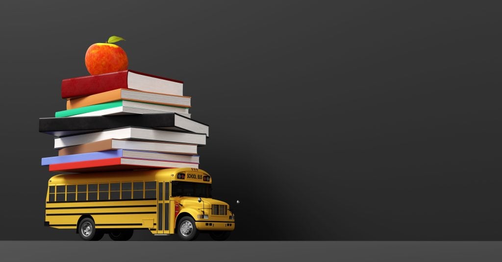 School bus with multiple books stacked on top of it 