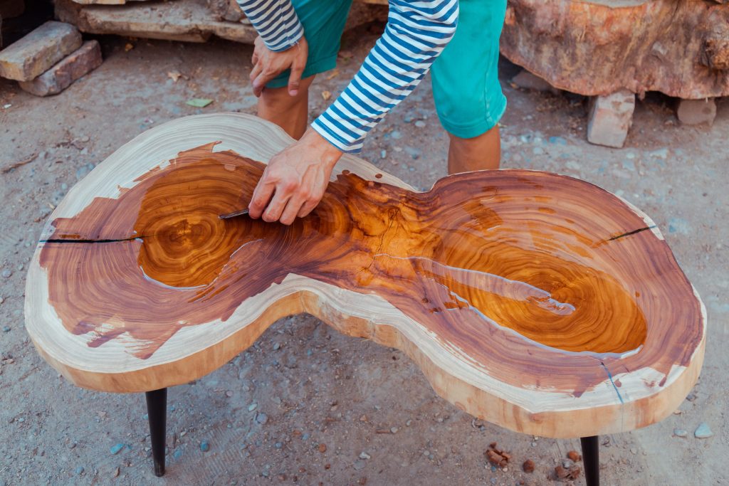 Woodworker pouring linseed oil on a table