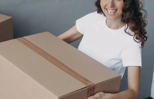 Woman carrying moving boxes in home