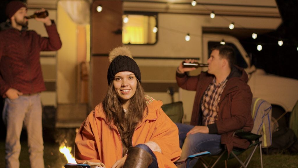 Girl sitting bundled up in front of RV on a cold night