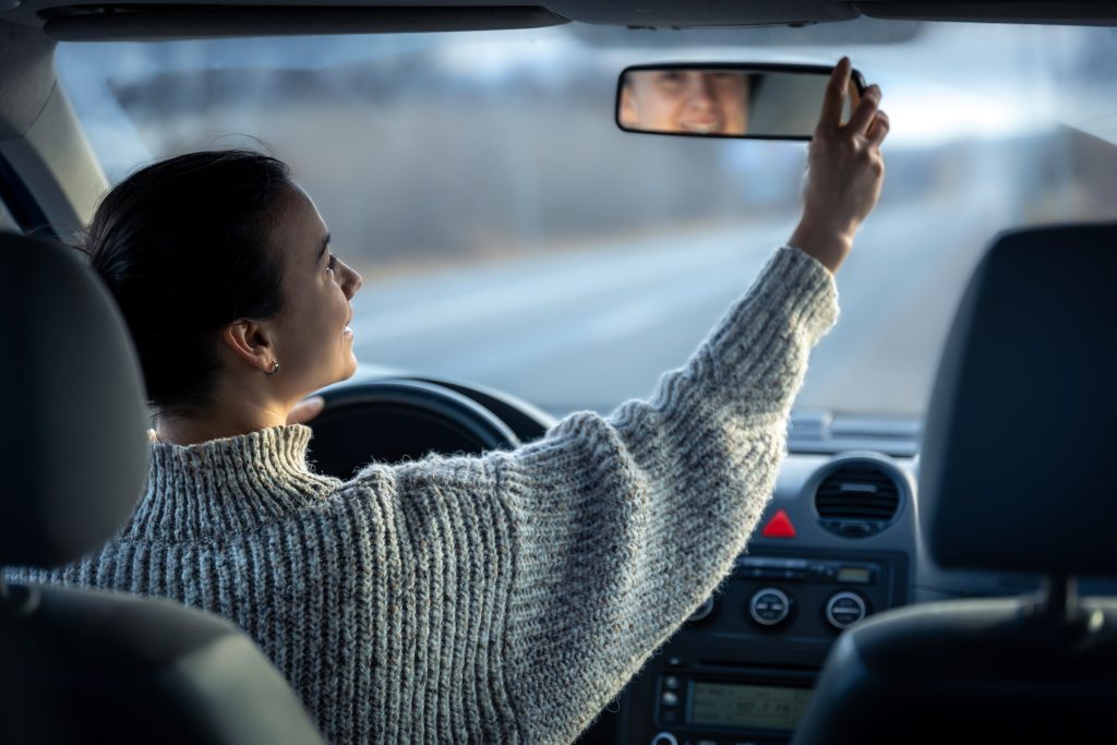 Woman checking mirrors in car to safely drive on highway