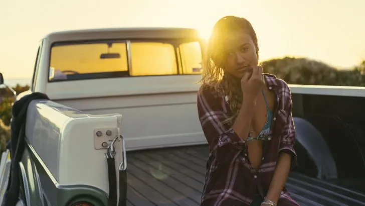 Woman sitting in the back of truck at sunset