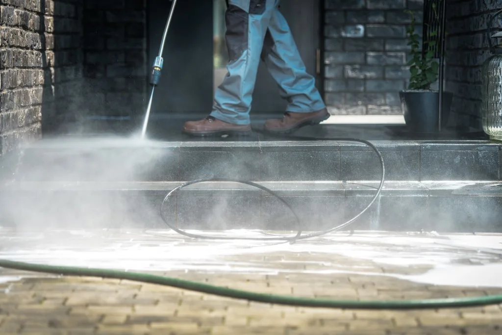 Man using pressure washer to clean patio