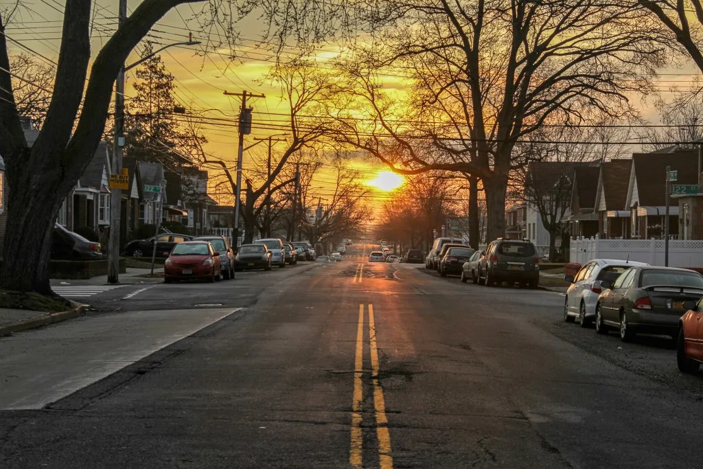 Residential neighborhood with car parked at sunset. 