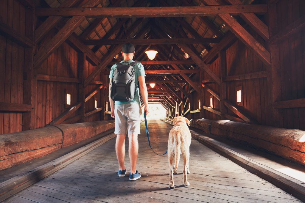Man walking dog across covered bridge in Alabama