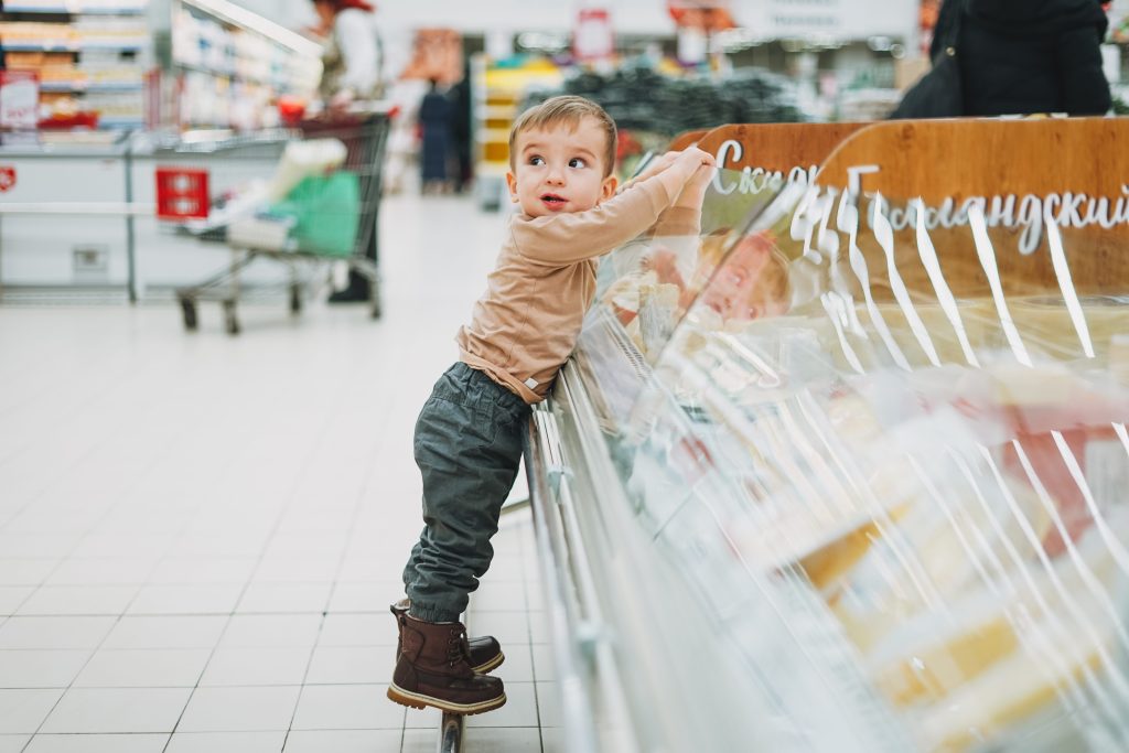 Little boy standing next to grocery store deli