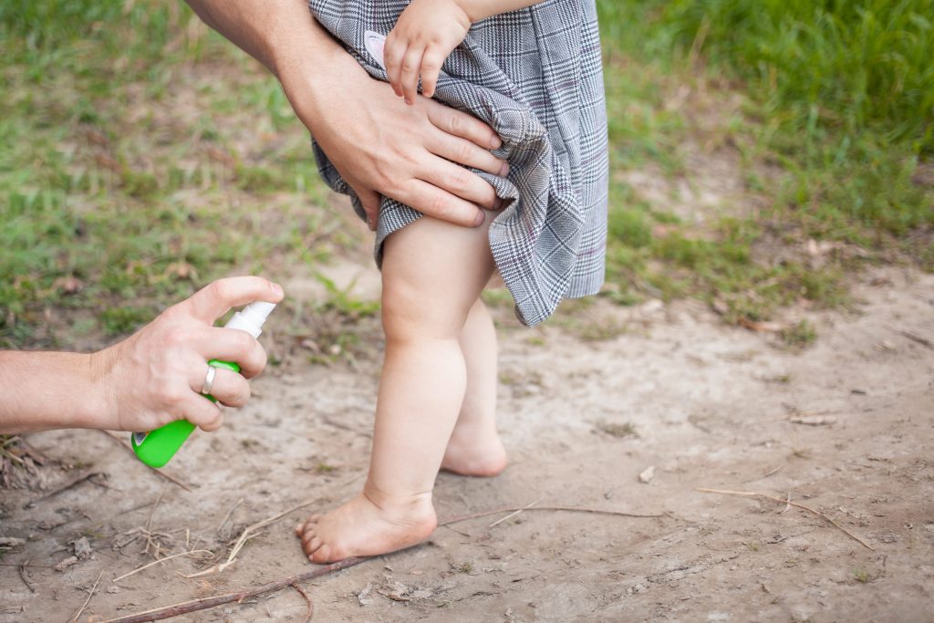 Little girl being sprayed in bug spray to prevent chiggers