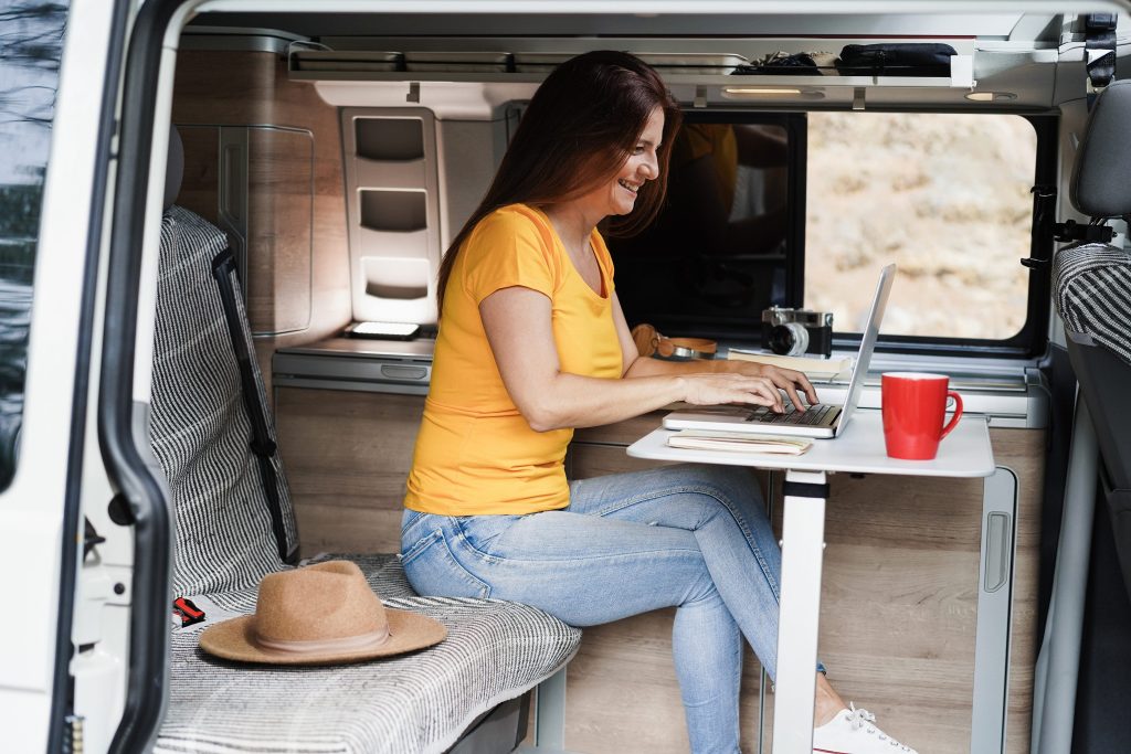 Woman working on laptop inside of small RV