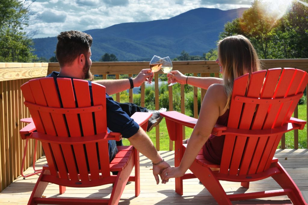 Couple drinking wine together on Adirondack chairs