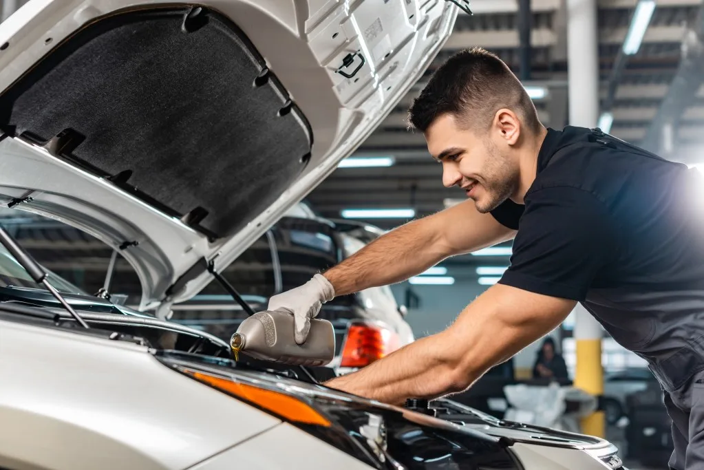 Mechanic pouring motor oil into car engine