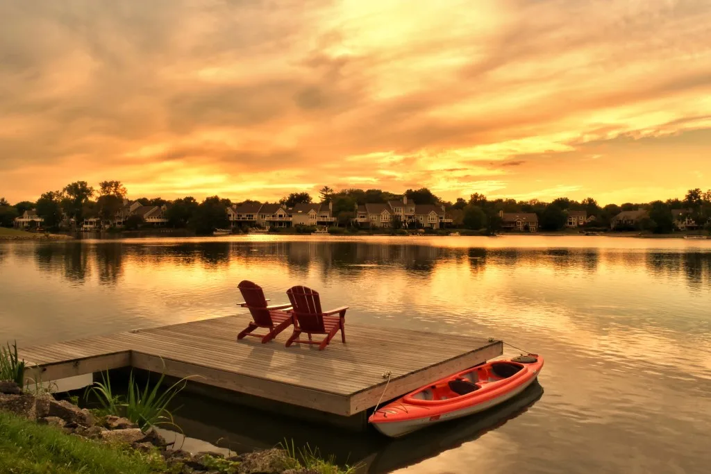 Two  Adirondack chairs on dock looking at sunset over lake
