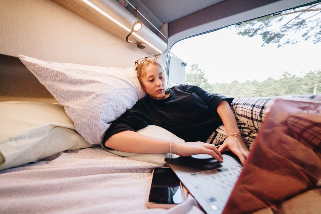 Girl streaming show on laptop in camper van
