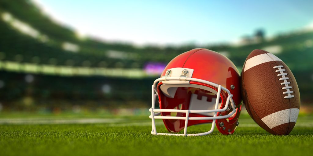 Football and helmet on football field
