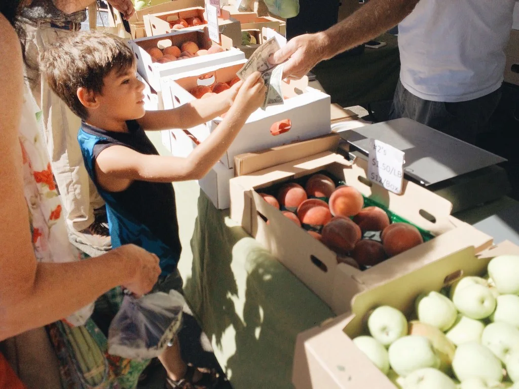 Little boy buying fruit at farmers market