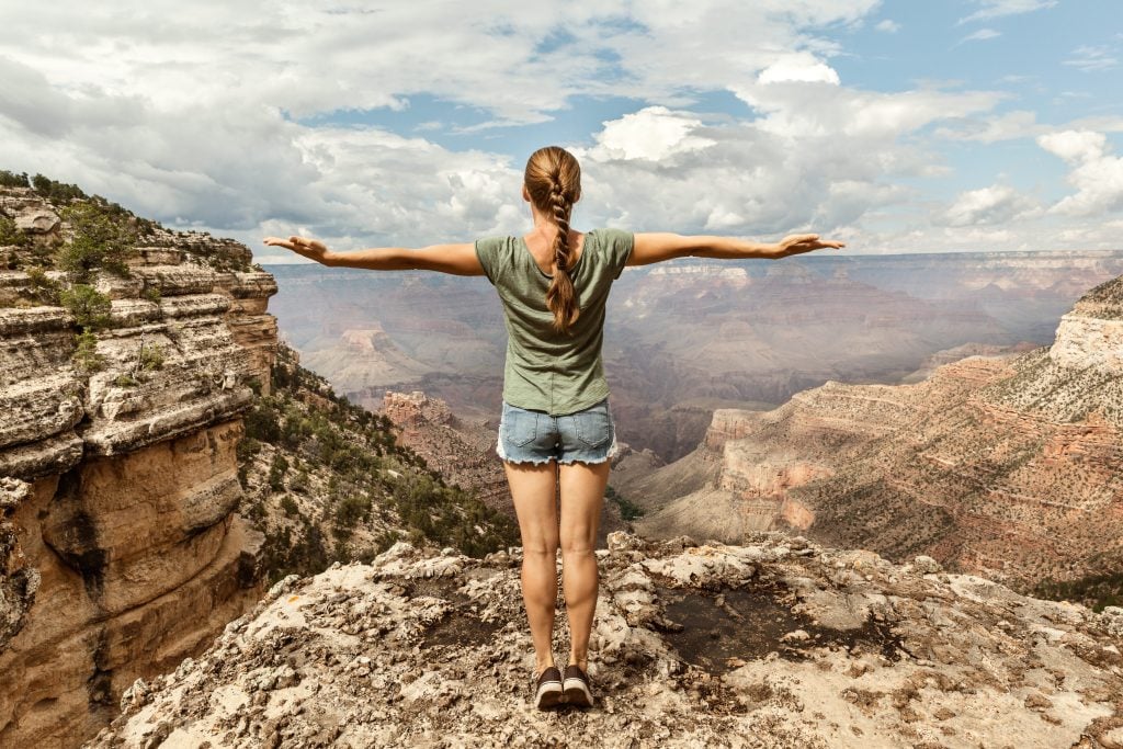 Woman posing with arms outstretched at the top of the Grand Canyon